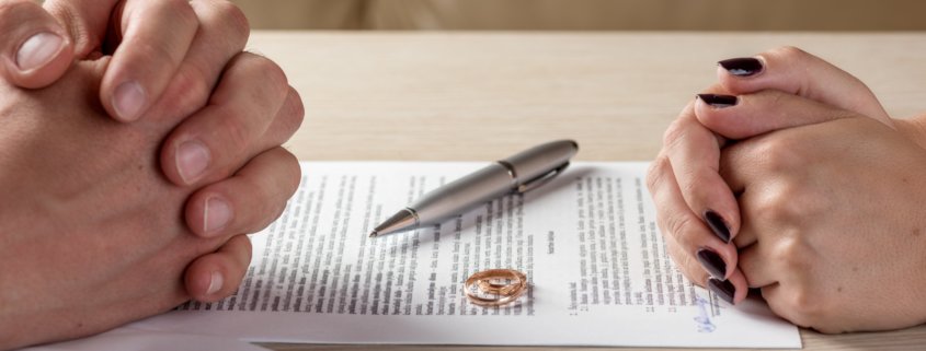 Two rings sit on top of a divorce form with two ex spouses discussing alimony