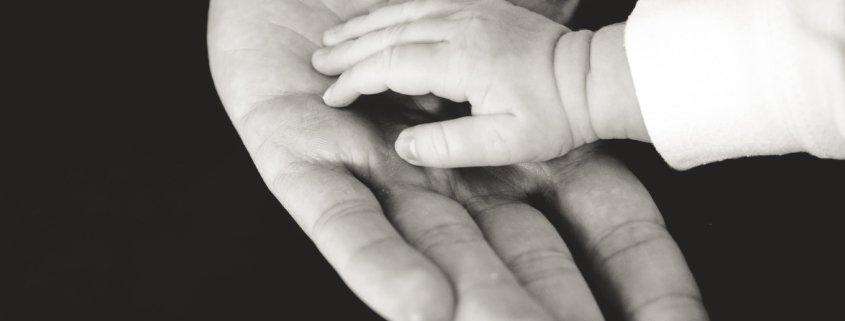 Grandparent holding babies hand. Learn about grandparents rights to child custody