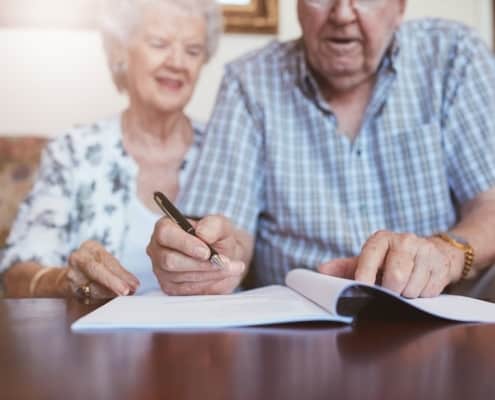 An elderly couple work on their wills after speaking with an attorney for wills and trusts.