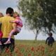 A man stands in a field carrying 2 children as a third runs ahead. A child custody lawyer helps him protect his rights