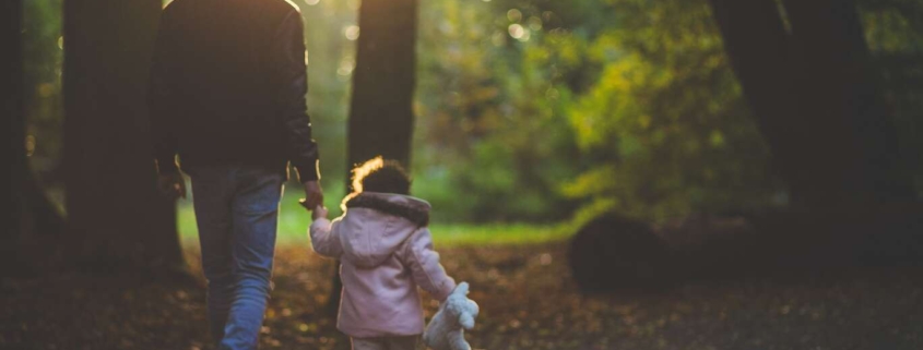 Father and child walk through the forest after he requests child support modification from courts