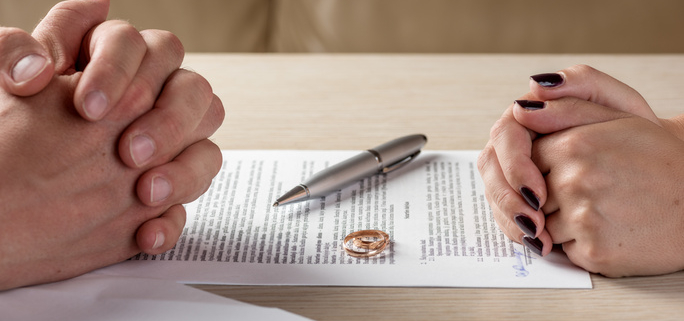 A couple sits opposite each other over paperwork discussing collaborative divorce vs mediation