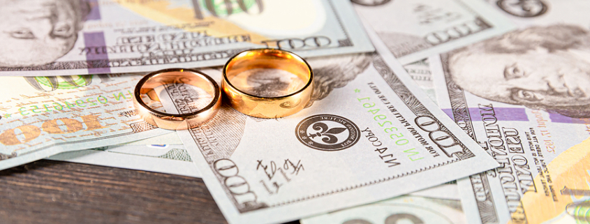Wedding bands sitting on top of money on a table. High Net Worth Divorce