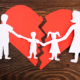 Paper cutout silhouette of a family split apart on a paper heart, child mediation.