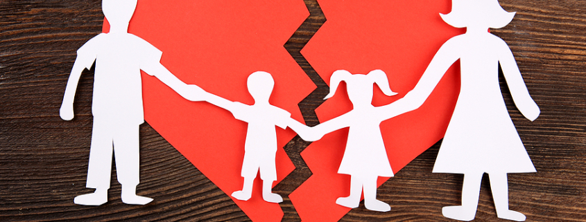 Paper cutout silhouette of a family split apart on a paper heart, child mediation.