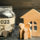 Glass jar with coins labeled 2023 and wood cutouts of family and wooden house. Estate Planning Tips to Keep Money in the Family