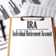 Paper on clipboard with IRA on a chart background. retirement accounts