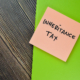 Concept of Inheritance Tax write on sticky notes isolated on Wooden Table. inheritance tax