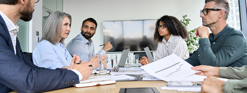 Diverse professional executive business team people discuss project sitting at meeting table in board room. Multiethnic company managers brainstorm financial plan working together in boardroom. business assets