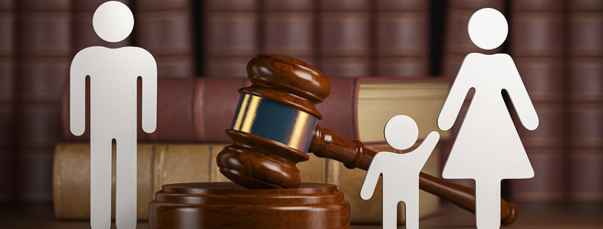 A gavel and legal books with paper cutouts of a family, representing the legal process of altering or breaking a parent-child relationship.
