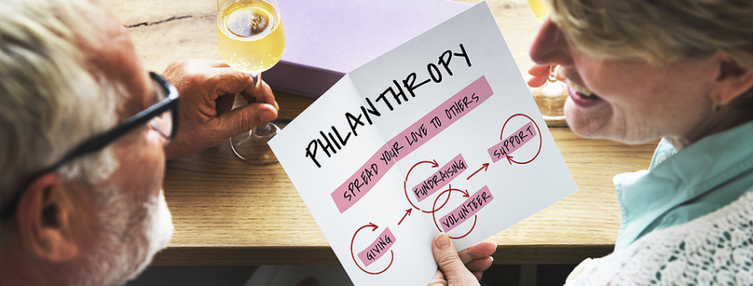 Older couple discussing a charitable giving plan, holding a paper that outlines the concepts of philanthropy, fundraising, volunteering, and support.