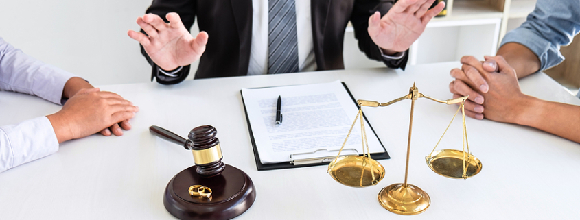 Couple meeting with lawyer to resolve a high-conflict divorce. Sitting at table with clip board & gavel.