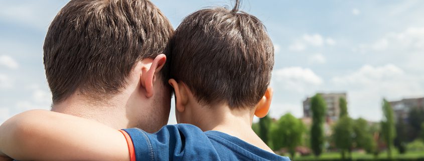 The back view of a legal guardian and the boy he is caring for.