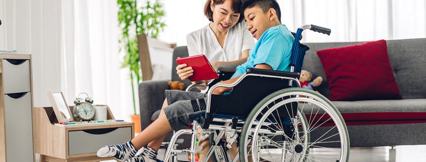 An Asian physiotherapist supports and interacts with a disabled child, offering care and guidance in a warm, engaging environment—a visual representation of the compassion and planning involved in creating a special needs trust.