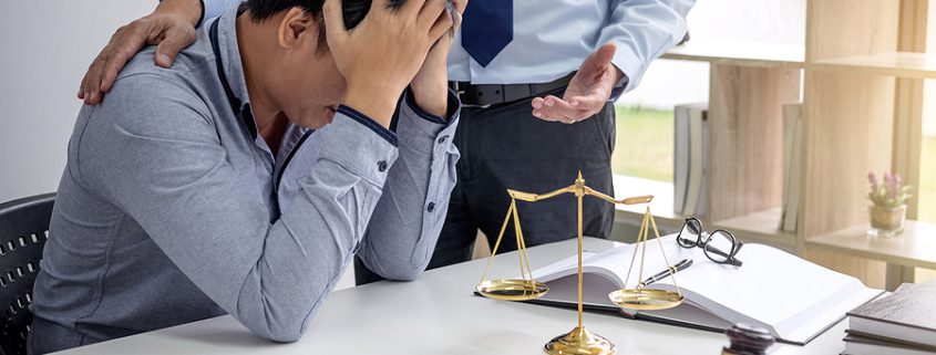 Judge's gavel and scales of justice on a desk as two lawyers discuss documents—representing legal outcomes when you die without a will.