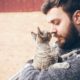 Man in sweater holding his cat on a balcony, symbolizing the love and care a pet trust can provide for pets’ future needs.