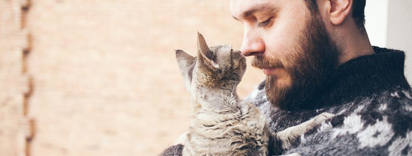 Man in sweater holding his cat on a balcony, symbolizing the love and care a pet trust can provide for pets’ future needs.