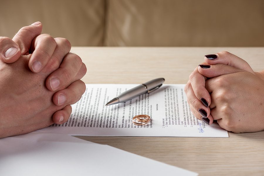 Hands of a couple signing legal documents related to divorce or annulment.