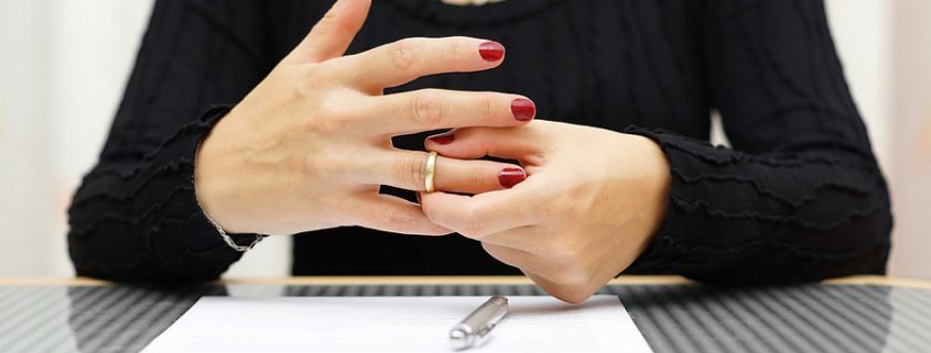 Woman removing wedding ring from her hand, symbolizing annulment and the end of a marriage.