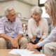 Financial advisor discussing estate planning options with unmarried couples, reviewing documents and future investment plans.