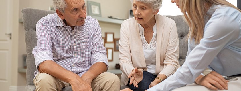 Financial advisor discussing estate planning options with unmarried couples, reviewing documents and future investment plans.
