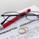 A lawyer and couple reviewing and signing prenuptial agreements at a desk, symbolizing financial planning and legal protection before marriage.