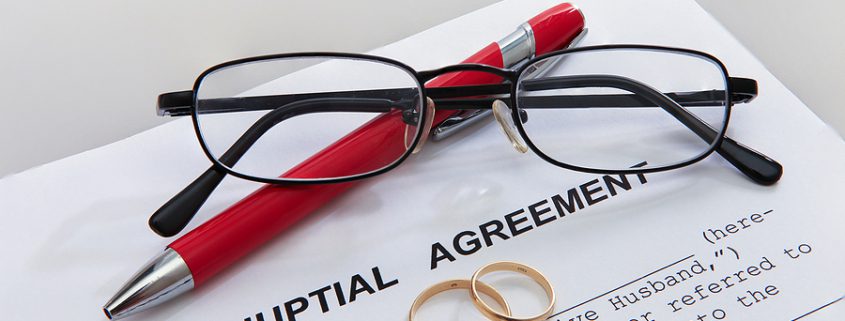 A lawyer and couple reviewing and signing prenuptial agreements at a desk, symbolizing financial planning and legal protection before marriage.