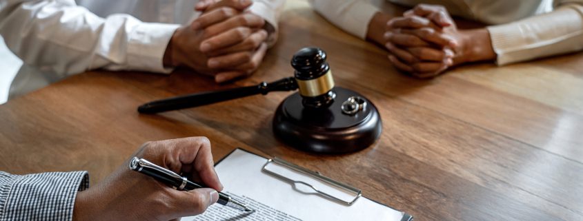 Unhappy couple discussing no-fault divorce with a senior male lawyer, symbolizing the emotional and legal challenges of ending a marriage.
