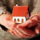 Woman holding a small house model in her hands, symbolizing life insurance trusts, financial protection, and secure future planning.
