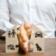 A man holding a small house in his hand symbolizing divorce, property division, and child custody decisions.