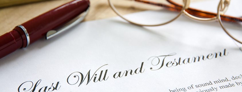 Document labeled “Last Will and Testament” placed on a wooden desk beside a pen, symbolizing estate planning and legal preparation.