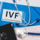 Blue folder labeled IVF (in vitro fertilization) with patient file and medical documents on a desk, representing fertility treatment and IVF planning.