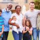 Outdoor portrait of a smiling multi-generation, mixed-race family standing together in their garden at home, capturing the joy and connection of blended families across generations.