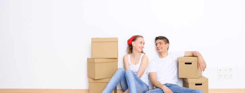Young couple resting on the floor after moving into a new home, symbolizing cohabitation and starting life together.