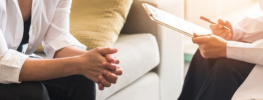 Mental health consultation between a psychiatrist and a stressed female patient during a counseling session, discussing emotional well-being and mental health concerns in a clinical setting.
