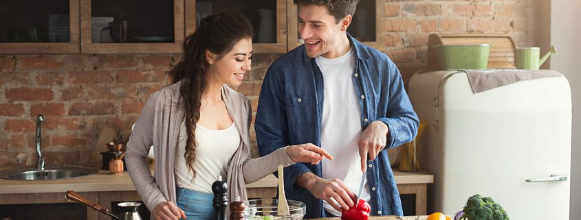 Happy couple cooking together at home, representing modern cohabitation and shared living.
