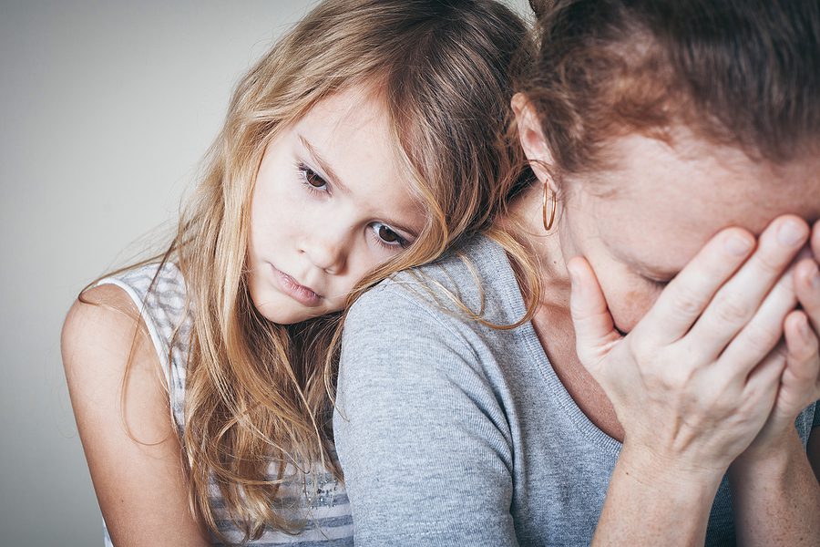Sad daughter hugging her mother for comfort, illustrating the emotional impact of mental health challenges on families.