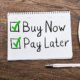 Buy Now Pay Later notepad on a desk with pen and coffee, illustrating marital debt considerations