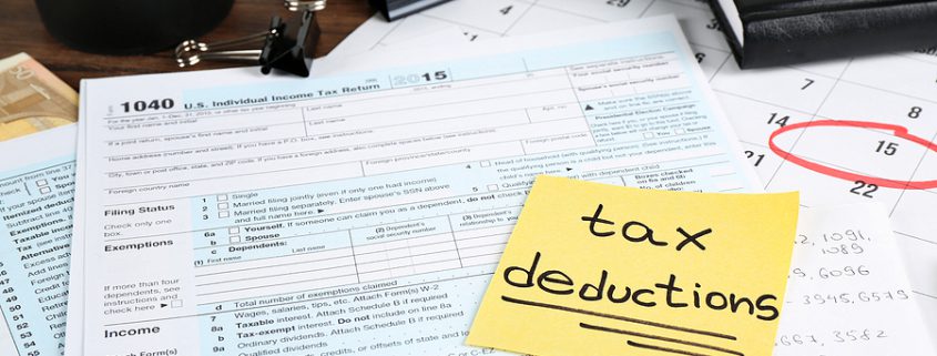 Tax Deductible expenses concept with tax deductions paper and individual tax return form on a table.