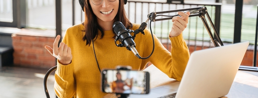 Digital assets content creator laughing on a podcast while recording with smartphone and headphones
